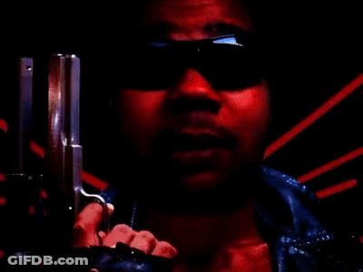 A Man Wearing Sunglasses Is Pointing A Gun At The Camera In A Red Background . GIF