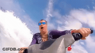 A Man Wearing Sunglasses Is Riding A Jet Ski On A Body Of Water . GIF