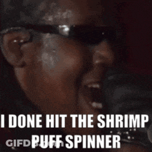A Man Wearing Sunglasses Is Screaming That He Has Done Hit The Shrimp Puff Spinner GIF