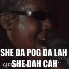 A Man Wearing Sunglasses Is Singing Into A Microphone With The Words She Da Pog Da Lah She Dah Cah . GIF