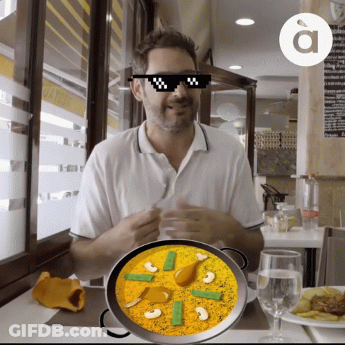 A Man Wearing Sunglasses Is Sitting At A Table With A Bowl Of Food GIF