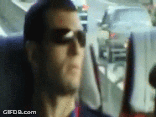 A Man Wearing Sunglasses Is Sitting In A Car Looking Out The Window GIF
