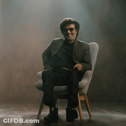 A Man Wearing Sunglasses Is Sitting In A Chair And Smiling GIF