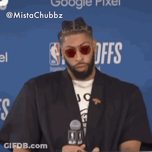 Man Wearing Sunglasses Sitting In Front Of NBA Logo GIF