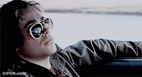 A Man Wearing Sunglasses Is Sitting In The Back Seat Of A Car . GIF