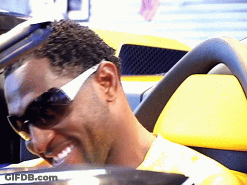 A Man Wearing Sunglasses Is Smiling In A Yellow Car GIF