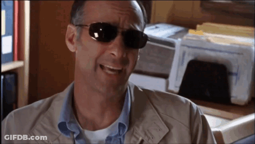 A Man Wearing Sunglasses Is Smiling In Front Of A Printer . GIF