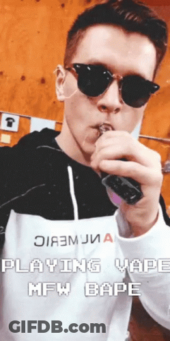 A Man Wearing Sunglasses Is Smoking An Electronic Cigarette With The Words " Playing Vaping Mfw Bape " Below Him GIF