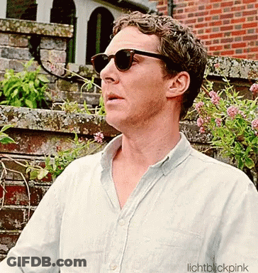 A Man Wearing Sunglasses Is Standing In Front Of A Brick Building GIF