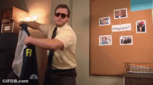 A Man Wearing Sunglasses Is Standing In Front Of A Bulletin Board That Says " Pregnant " GIF