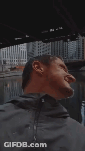 A Man Wearing Sunglasses Is Standing In Front Of A City Skyline . GIF