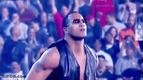 A Man Wearing Sunglasses Is Standing In Front Of A Crowd . GIF
