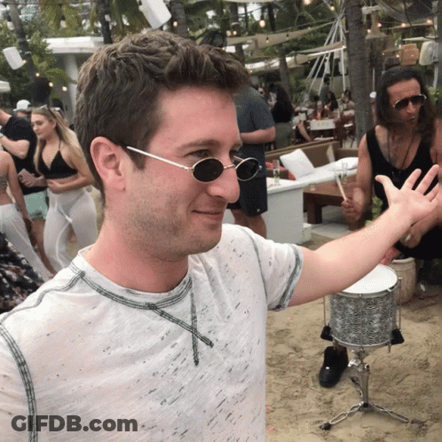 A Man Wearing Sunglasses Is Standing In Front Of A Drum GIF