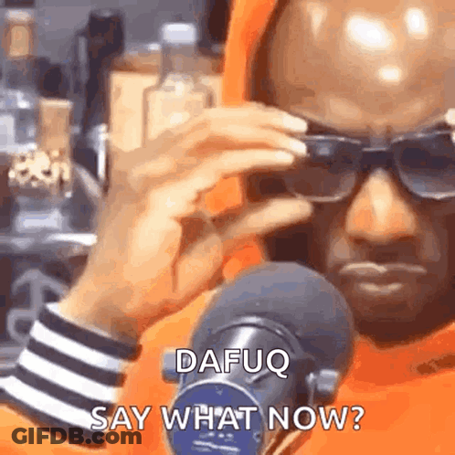 A Man Wearing Sunglasses Is Standing In Front Of A Microphone And Talking Into It . GIF