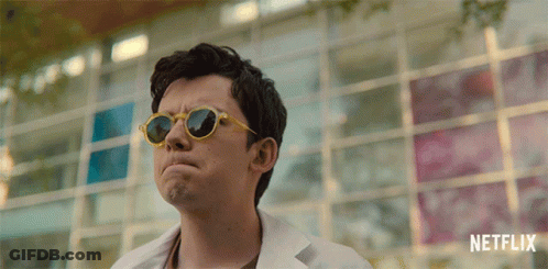A Man Wearing Sunglasses Is Standing In Front Of A Netflix Logo GIF