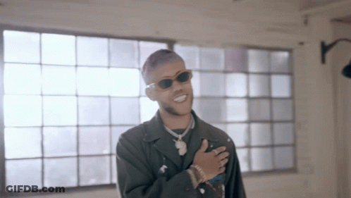 A Man Wearing Sunglasses Is Standing In Front Of A Window And Smiling GIF