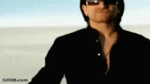 A Man Wearing Sunglasses Is Standing In The Desert . GIF
