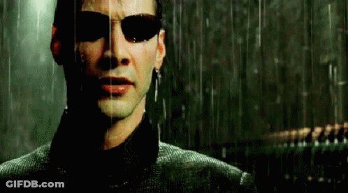A Man Wearing Sunglasses Is Standing In The Rain And Looking At The Camera . GIF