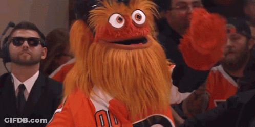 A Man Wearing Sunglasses Is Taking A Picture Of A Mascot In The Crowd GIF