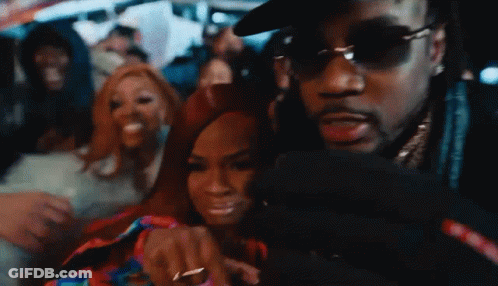 A Man Wearing Sunglasses Is Taking A Picture Of A Woman In A Crowd GIF