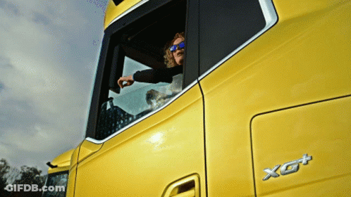 A Man Wearing Sunglasses Looks Out Of The Window Of A Yellow Truck GIF