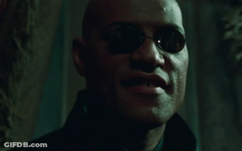 A Man Wearing Sunglasses Says " At Last " In A Dark Room GIF