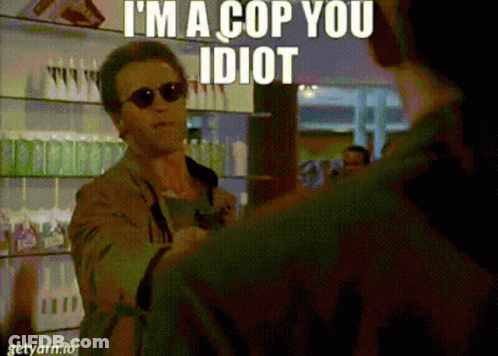 A Man Wearing Sunglasses Says I 'M A Cop You Idiot While Talking To Another Man GIF