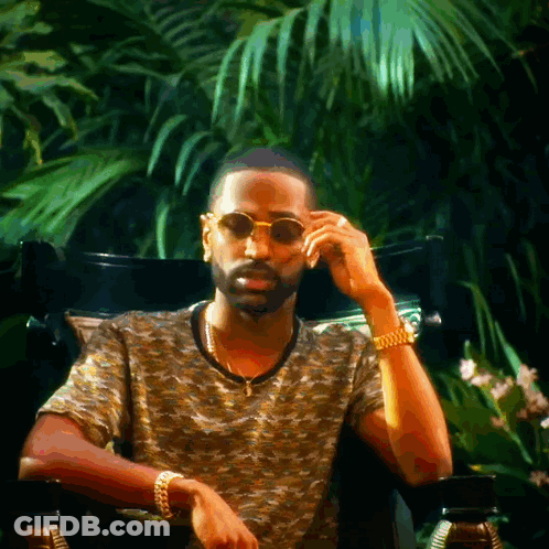 A Man Wearing Sunglasses Sits In A Chair GIF