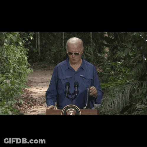 A Man Wearing Sunglasses Stands Behind A Podium With A United States Seal On It GIF