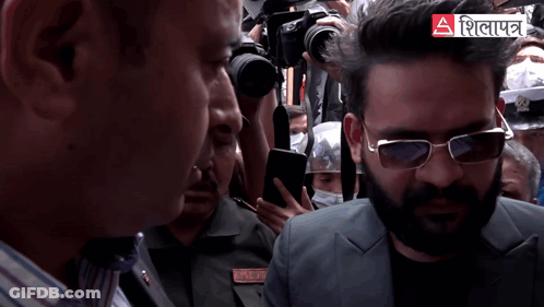 A Man Wearing Sunglasses Stands In A Crowd With A Sign That Says ' A ' GIF