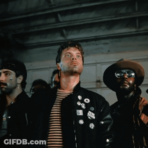 A Man Wearing Sunglasses Stands In Front Of A Cage GIF