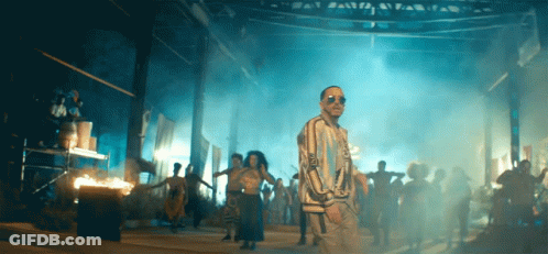 A Man Wearing Sunglasses Stands In Front Of A Crowd GIF