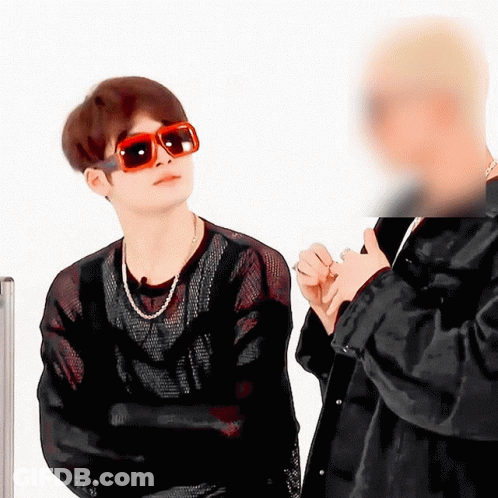 A Man Wearing Sunglasses Stands Next To Another Man In A Black Jacket GIF