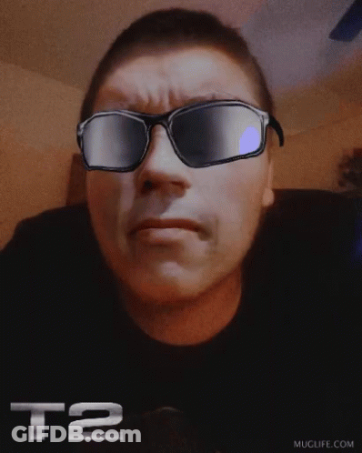 A Man Wearing Sunglasses With The Letters T2 On His Shirt GIF