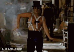 A Man Wearing Suspenders And A Top Hat Is Dancing In A Room . GIF