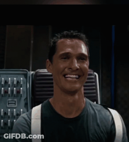 A Man Wearing Suspenders Is Smiling In Front Of A Machine GIF