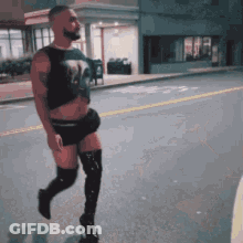 A Man Wearing Thigh High Boots And Shorts Is Walking Down A Street GIF