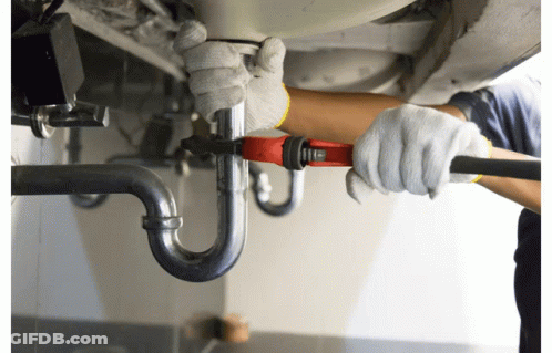 A Man Wearing White Gloves Is Working On A Pipe With A Wrench GIF