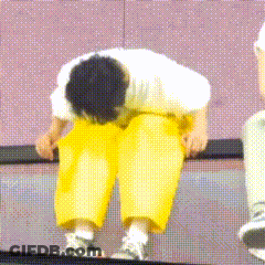 A Man Wearing Yellow Pants And A White Shirt Is Bending Over GIF