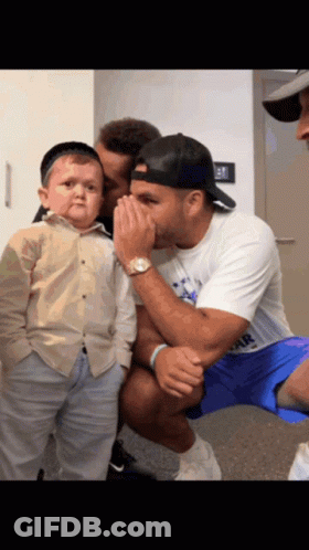 A Man Whispering Into Another Man 'S Ear While Holding A Small Boy GIF