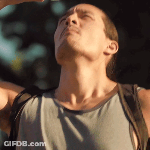 A Man With A Backpack Is Looking Up At The Sun GIF