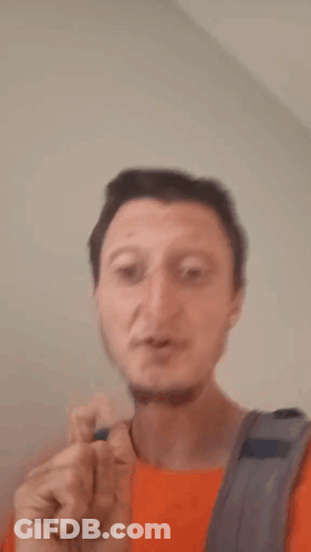 A Man With A Backpack Is Making A Shhh Gesture With His Finger To His Mouth . GIF