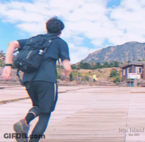 A Man With A Backpack Is Running On A Boardwalk With The Words Jeju Island Written On It GIF