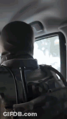 A Man With A Backpack Is Sitting In The Back Seat Of A Car Looking Out The Window GIF