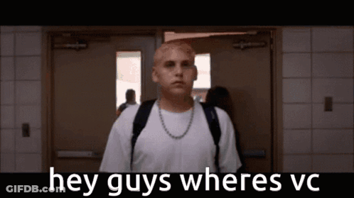 A Man With A Backpack Is Standing In A Hallway With The Words Hey Guys Wheres Vc Written Above Him . GIF
