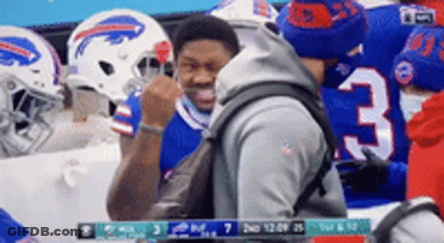 A Man With A Backpack Is Standing In Front Of A Group Of Buffalo Bills Football Players . GIF