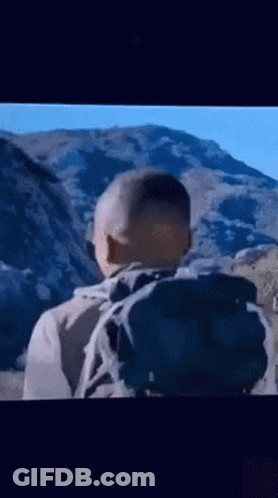 A Man With A Backpack Is Walking Through A Mountain Range . GIF