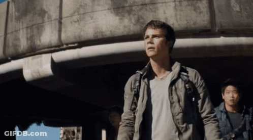 A Man With A Backpack Stands In Front Of A Concrete Building GIF