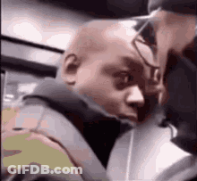 A Man With A Bald Head Is Sitting Next To Another Man On A Train . GIF