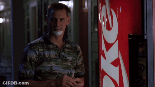 A Man With A Bandage Around His Mouth Stands In Front Of A Coke Machine GIF